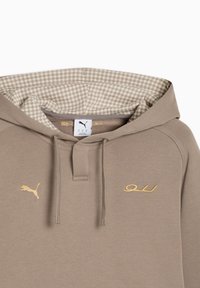 Μπεζ φούτερ Puma με κορδόνια και εσωτερική φόδρα στην κουκούλα με σχέδια, με χρυσλό λογότυπο Puma και κέντημα "LFC" στο στήθος.