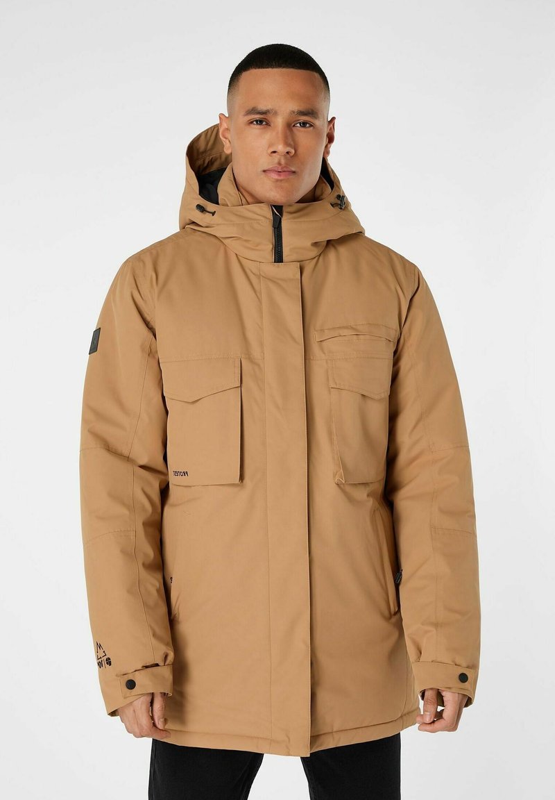 Braune isolierte Parka mit Kapuze, ausgestattet mit vier Fronttaschen, einem Reißverschluss und Markendetails an den Ärmeln. Strukturiertes Material.