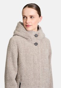 Beige wollen blend jas met een grote, comfortabele capuchon, twee zwarte knopen en zijzakken. Zachte textuur en rechte snit.