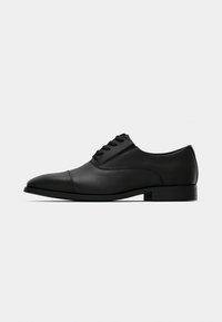 Chaussure habillée en cuir noir avec un bout pointu, une texture lisse, une fermeture à lacets et un talon plat minimaliste. Design classique et formel.