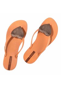 Chanclas naranjas de goma, con un acento metálico en forma de corazón en la correa y una plantilla estampada con herrajes marrones.