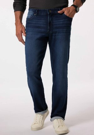 Donkerblauwe denim jeans met een rechte snit, twee voorkruiszakken en een klassieke knopen sluiting. Gecombineerd met off-white sneakers.