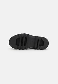 Zwarte sneakerzool met een gestructureerde grip, voorzien van drie horizontale strepen en een soepele boog. Geeft maat 37 aan de onderkant.