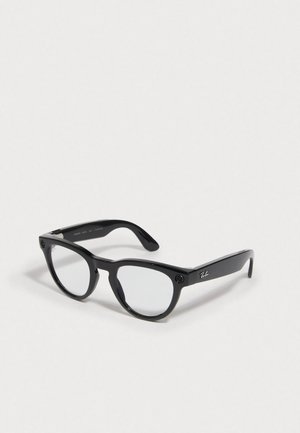 Lunettes en plastique noir avec verres transparents, de forme arrondie, et éléments accentués sur les côtés. Présente un logo sur la branche.