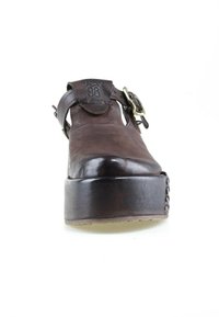 Chaussure plateforme en cuir marron avec semelle épaisse et boucle latérale, vue de face sur fond blanc.
