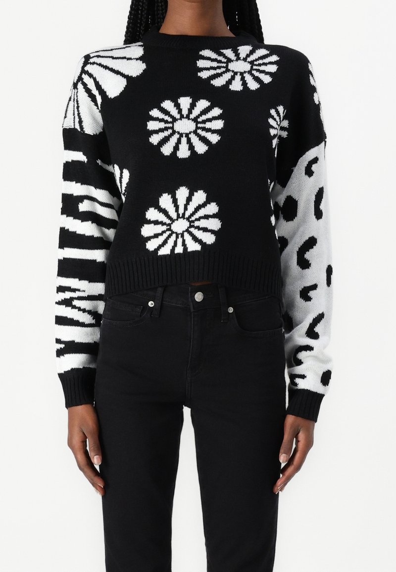 Black and white knitted sweater featuring large floral patterns, stripes, and a cropped design with ribbed cuffs and hem.