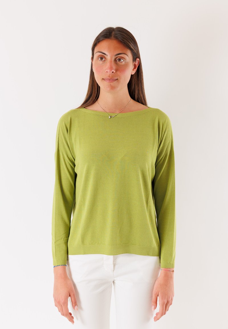 Maglione leggero a maniche lunghe di un verde vivace, con scollatura ampia e orlo a coste. Abbinato a pantaloni bianchi per un contrasto.