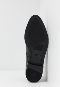 Semelle de chaussure habillée en cuir noir avec grip texturé, bout pointu, et taille 37 marquée par la marque Vagabond Shoemakers.