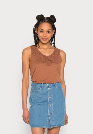 Top castanho sem mangas com decote bordado, combinado com uma saia de denim azul claro com botões à frente e bainha desfiada.