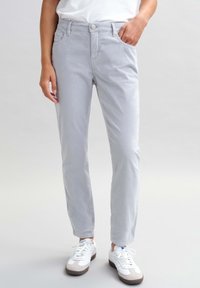 Světlé šedé kalhoty s rovný fit, s předními kapsami, zapínáním na knoflík a hladkým povrchem. Nosené s bílými sportovními botami.