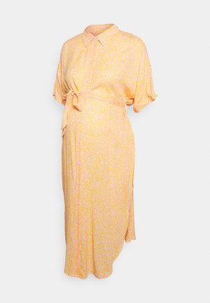 Vestido amarelo com padrão, mangas curtas, colarinho abotoado e um laço na cintura. Textura suave e silhueta em A, com comprimento até o joelho.
