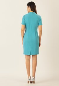 Türkises Kurzarmkleid mit taillierter Silhouette, Reißverschluss im Rücken und einer Länge bis zur Mitte des Oberschenkels. Es verfügt über einen Schlitz in der Mitte des Rückens und hat eine glatte Textur.