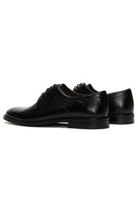 Zwarte leren schoenen met een gestructureerd oppervlak, ronde neus en een lage hak. Veters en subtiele stiksels zichtbaar.