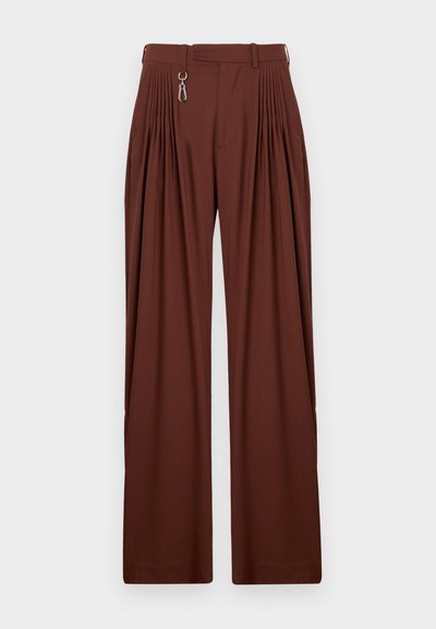 Pantaloni plisati maro cu un design cu picioare largi, având un accent cu fermoar și bucle pentru curea, realizati dintr-un material moale și texturat.