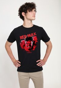 Černé bavlněné tričko se středně velkým grafickým motivem postavy Red Hulka v červené a černé barvě a výrazným textem na hrudi. Krátké rukávy a kulatý výstřih.