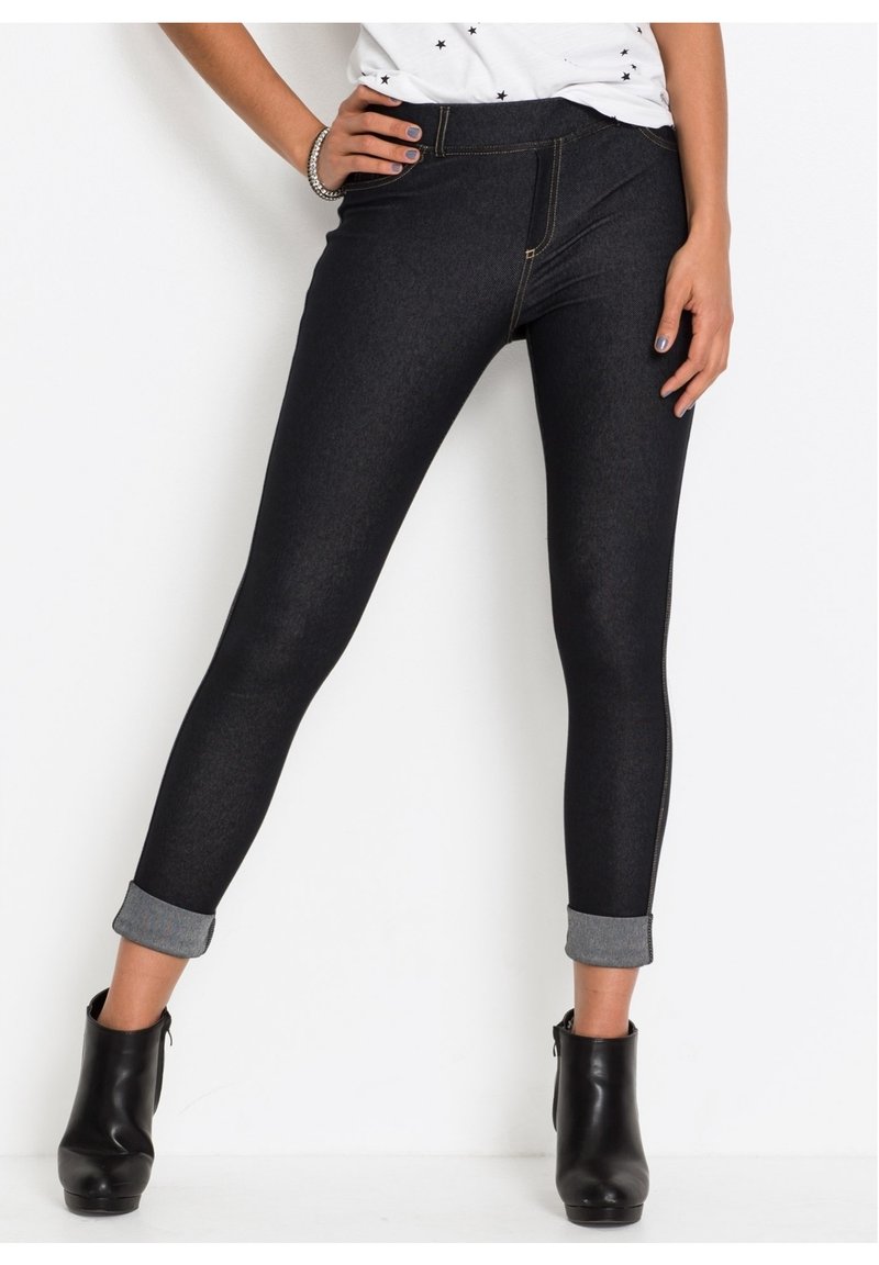 Czarne legginsy dżinsowe o dopasowanym kroju, jasnoniebieskie podwijane mankiety oraz kontrastowe złote szwy wzdłuż szwów. Materiał wydaje się elastyczny i teksturowany.