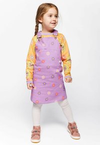 Lilla puuvillane kleit lillemustriga, reguleeritavad rihmad, esikott, kantud pika varrukaga kollase särk üle, koos heledate legging'ite ja kingadega.
