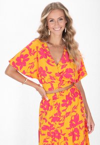 Gelbes Blumen-Top mit pinken Blumen, V-Ausschnitt, lockere Ärmel, kombiniert mit einem passenden Rock mit elastischem Taillenbund.