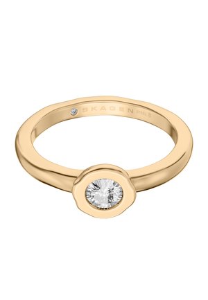 Goldfarbener Ring mit einem runden, klaren Edelstein in einer Lünettenfassung und einer Gravur innen am Ring.