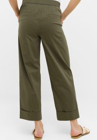 Olivengrønne vide bukser med afslappet pasform, elastisk talje og to baglommer. Bunden er opkrøllet for et afslappet look.