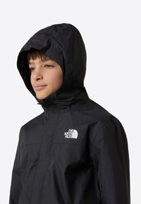 Schwarze leichte Jacke mit Kapuze und Frontreißverschluss. Verfügt über das weiße The North Face Logo auf der Brust. Glatte Textur, für den Outdoor-Einsatz konzipiert.