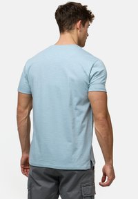 Hellblaues T-Shirt mit kurzen Ärmeln und Rundhalsausschnitt, aus weichem Stoff gefertigt. Verfügt über einen geraden Schnitt und kleine Seitenschlitze am Saum.
