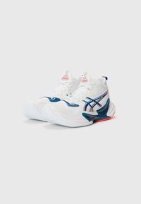 Witte sportieve schoenen met een gestructureerde bovenkant, donkerblauwe accenten en rode branding. Beschikt over een gebogen zool en een opvallend vetersysteem.