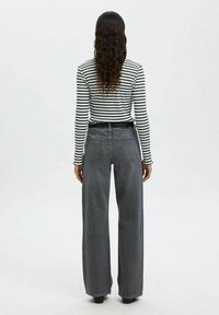 Gestreiftes Langarmshirt, kombiniert mit hochtaillierten, weiter geschnittenen grauen Jeans. Die Jeans verfügen über ein klassisches Fünf-Taschen-Design und einen robusten Bund.