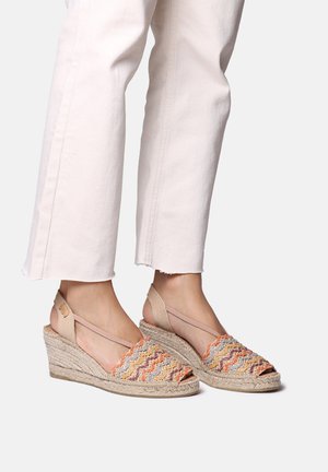 Wedge sandals with woven multicolored fabric, predominantly orange and beige, and a braided jute midsole. Adjustable ankle straps.
