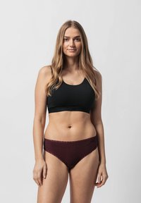 Top in cotone nero a cropped abbinato a lingerie bordeaux con pizzo. Il top presenta un scollo rotondo e un design aderente.