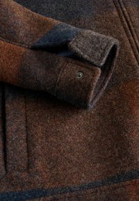 Brown, gray, and navy woolen fabric features a soft, textured surface with a button detail on the cuff and a horizontal stripe pattern.