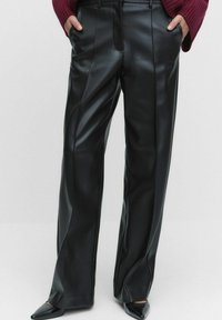 Musta keinonahasta valmistetut leveät housut, joissa on sileä pinta ja etusaumat. Ominaisuuksiin kuuluu korkea vyötärö ja sivutaskut.