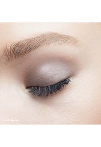 Close-up van een oog met een stoffige mauve oogschaduw op het ooglid, zwarte wimpers en een lichte huidtextuur rondom het oog.