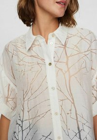 Lettrig, gennemsigtig skjorte med knapper i hvid med et tryk af grene i blød beige. Har klassisk krave og korte oprullet ærmer.
