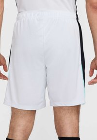 Witte sportshorts met een elastieken tailleband, voorzien van zwarte zijpanelen en turquoise accenten langs de naden. Soepele textuur.