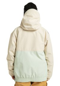 Ľahká, dvojfarebná bunda s krémovým vrchným dielom a mätovo zeleným spodným dielom, vybavená priliehavou kapucňou a elastickým pásom pre pohodlné nosenie.