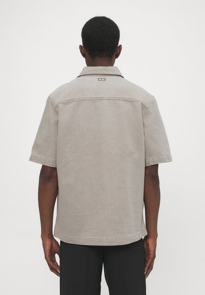 Korte mouwen shirt van lichtgrijze stof met een relaxte pasvorm, voorzien van een kraag, logodetail op de achterkant en een effen structuur.