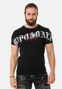 Schwarzes Baumwoll-T-Shirt mit kurzen Ärmeln, das auff älligen weißen und roten grafischen Text auf der Vorderseite zeigt. Lässige Passform mit Rundhalsausschnitt.