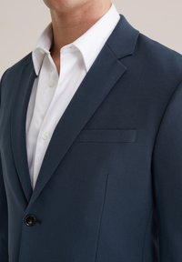 Marineblå blazer med slag, enkel knappstängning och bröstficka. Tillverkad av mjukt tyg med en skräddarsydd passform.