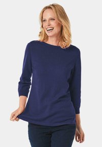 Dunkelblauer Pullover mit Rundhalsausschnitt, 3/4-Ärmeln und weicher Textur, kombiniert mit dunklen Jeans.