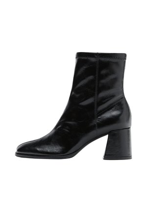 Bottine en cuir noir brillant avec bout pointu et talon bloc, vue latérale sur fond blanc.