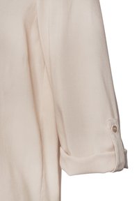 Blusa beige chiaro con maniche arrotolate, realizzata in un tessuto morbido. Presenta un dettaglio con bottone sulla manica per una chiusura sicura.