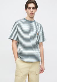 Ριγέ μπλουζάκι σε γκρι και λευκό, με στρογγυλή λαιμόκοψη και τσέπη στο αριστερό στήθος με λογότυπο. Κοντά μανίκια και άνετη εφαρμογή.