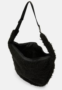 Sac à bandoulière en tissu noir duveteux avec un extérieur texturé, des finitions en cuir noir et une poche zippée intérieure. Doté d'une bandoulière robuste.