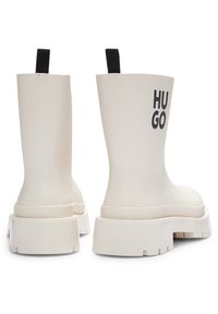 Rubberen enkelboots in crème met een stevige zool. Voorzien van een zwart "HUGO" logo en een trekband voor gemakkelijke aan- en uittrekking. Glad van structuur, modern design.