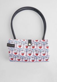 Rosa mönstrad handväska med svarta handtag, som har ett upprepat mönster av katter och hjärtan. Inkluderar en svart tryckknappslås.