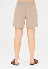 Beiga bomullsshorts med elastisk midja, med sidofickor och rak snitt, matchade med bruna slip-on skor.