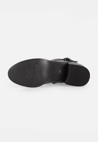 Black leather shoe sole with a textured design, branding, and a size marking. Features a smooth finish and a slight heel for stability.