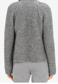 Šedý svetr, texturovaná pletenina, vysoký límec, raglánové rukávy a mírně zkrácený rovný lem. Vyznačuje se jemným, chlupatým vzhledem.