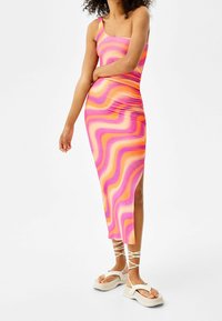 Padnoucí midi šaty s vícebarevným vlnkovým vzorem v růžové, oranžové a žluté. Vyrobené z hladkého materiálu, s čtvercovým výstřihem a bočním rozparkem.